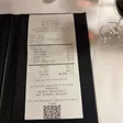A printed Empire Steak House receipt resting in a black check presenter on a white tablecloth.